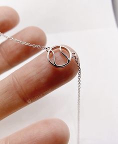 a hand holding a silver necklace with a ball on it