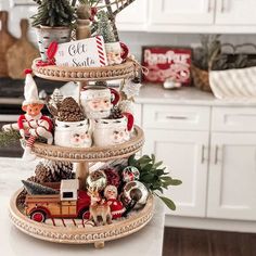 a three tiered tray with christmas decorations on it in the middle of a kitchen