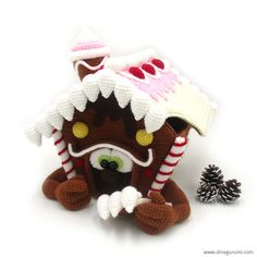 a crocheted gingerbread house with a pine cone