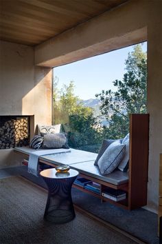 a living room with a couch, table and fire place in front of a large window