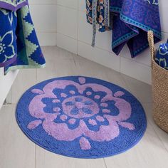 a blue and purple rug in a bathroom next to towels hanging on the wall,