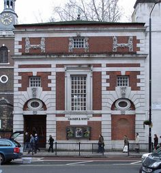 two people walking past an old brick building