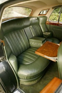 the interior of an old car with green leather seats and wood table in center console