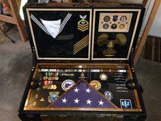 an open suitcase with medals and other items in it's display case on the floor