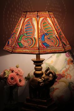 an elephant lamp on a table next to a vase with flowers and a wallpaper