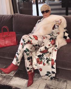 a woman sitting on top of a couch next to a red purse