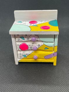 a small wooden table with drawers painted yellow and pink, blue and white polka dots