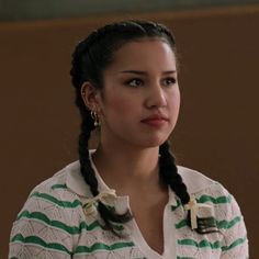 a woman with braids in a green and white striped shirt looking off to the side