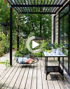 a patio with a swing chair, table and potted plants on the outside deck