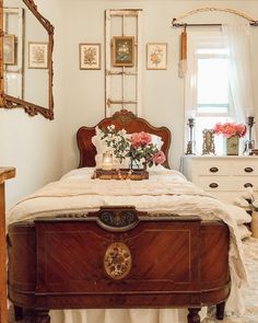 a bed sitting in a bedroom next to a dresser with flowers on top of it