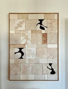 an abstract painting with black and white shapes on it's side, hanging on the wall