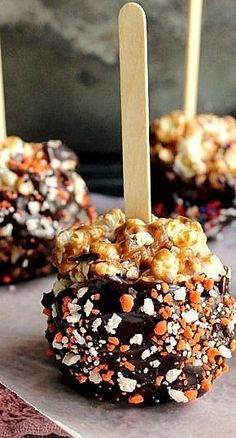 chocolate covered caramel popcorn balls with wooden skewers on a tablecloth, ready to be eaten