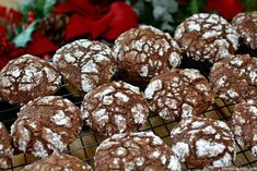 chocolate crinkle cookies with powdered sugar on a cooling rack next to red flowers