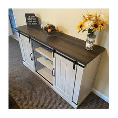 an entertainment center with two vases and flowers on the top shelf next to it