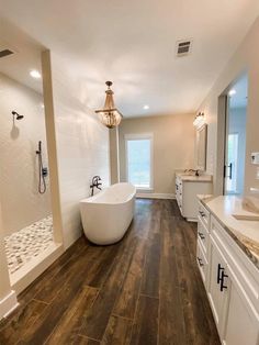 a large bathroom with wood flooring and white bathtub in the middle of it