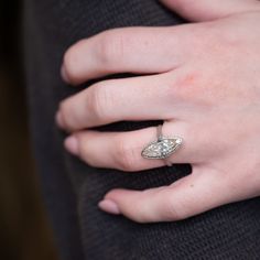 a close up of a person's hand with a diamond ring on their finger