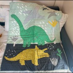 a child's bed with a dinosaur quilt on it