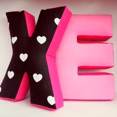 the letter e is made out of pink and black paper with white hearts on it