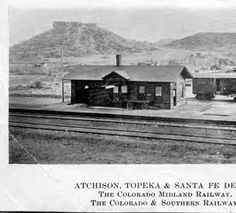 an old black and white photo of a train station with mountains in the background,