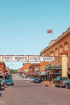 cars are parked on the street in front of an old brick building with a sign that says fort worth stock yards