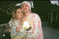 a man standing next to a woman holding a flower