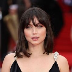 a close up of a person wearing a black dress with bangs on her head and shoulder