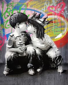 two children sitting on the ground in front of graffiti