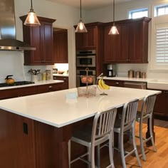 a large kitchen with wooden cabinets and white counter tops, along with stainless steel appliances