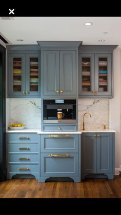 a kitchen with gray cabinets and gold handles on the countertop, along with a white marble counter top