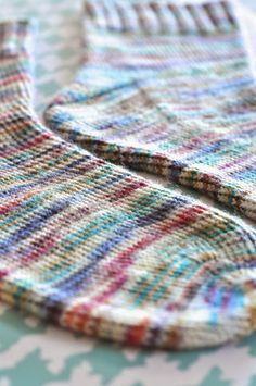 a pair of colorful socks sitting on top of a white and blue tablecloth covered in multicolored yarn