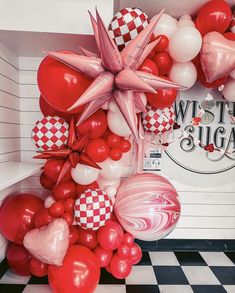 red and white balloons in the corner of a room with a checkered flooring