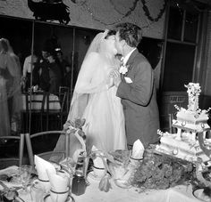 a bride and groom kissing in front of a table full of wedding cake at their reception