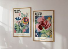 two framed posters hang on the wall next to each other, with flowers in bloom