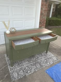 a green dresser sitting on top of a rug next to a garage door