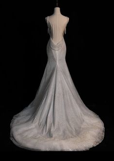 the back of a white wedding dress on a mannequin head stand in front of a black background