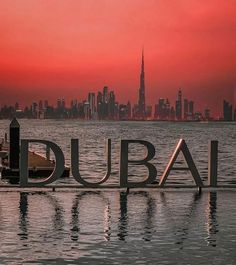 the word dubai is in front of a cityscape with skyscrapers at sunset