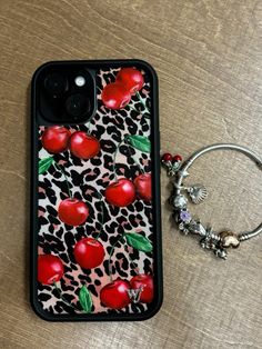 an iphone case with red apples on it next to a keychain and ring