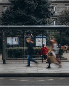 blurry image of people walking in front of a bus stop