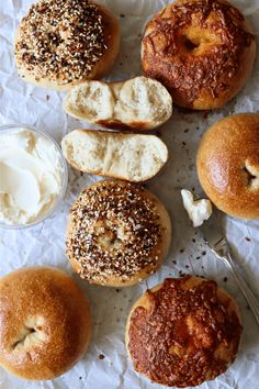 an assortment of bagels and cream cheeses on wax paper