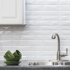 a kitchen sink sitting under a faucet next to a green bowl on top of a counter