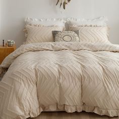 a bed with white comforter and pillows in a room next to a wall mounted clock