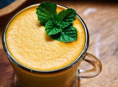 a glass mug filled with liquid and topped with a green leaf