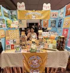 a woman standing in front of a table with pictures and cards on it at an event