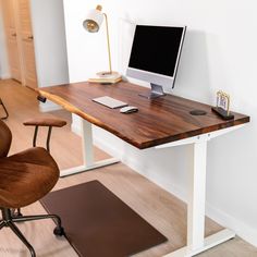 a desk with a computer on it and a chair next to it in a room