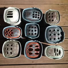 six ceramic pots with holes in them sitting on a wooden surface