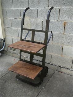 a wooden chair sitting on top of a metal cart next to a brick wall in front of a building