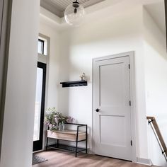 an empty room with a white door and some plants on the shelf next to it