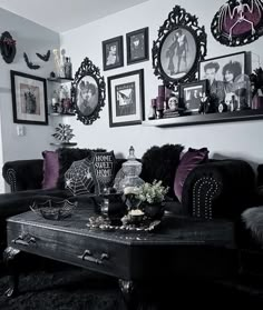 a living room filled with black furniture and pictures on the wall above it's coffee table