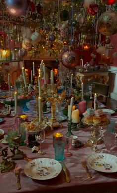 the table is set with many plates and silverware, candles, and other decorations