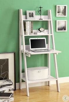 a computer desk with a laptop on top of it in front of a green wall